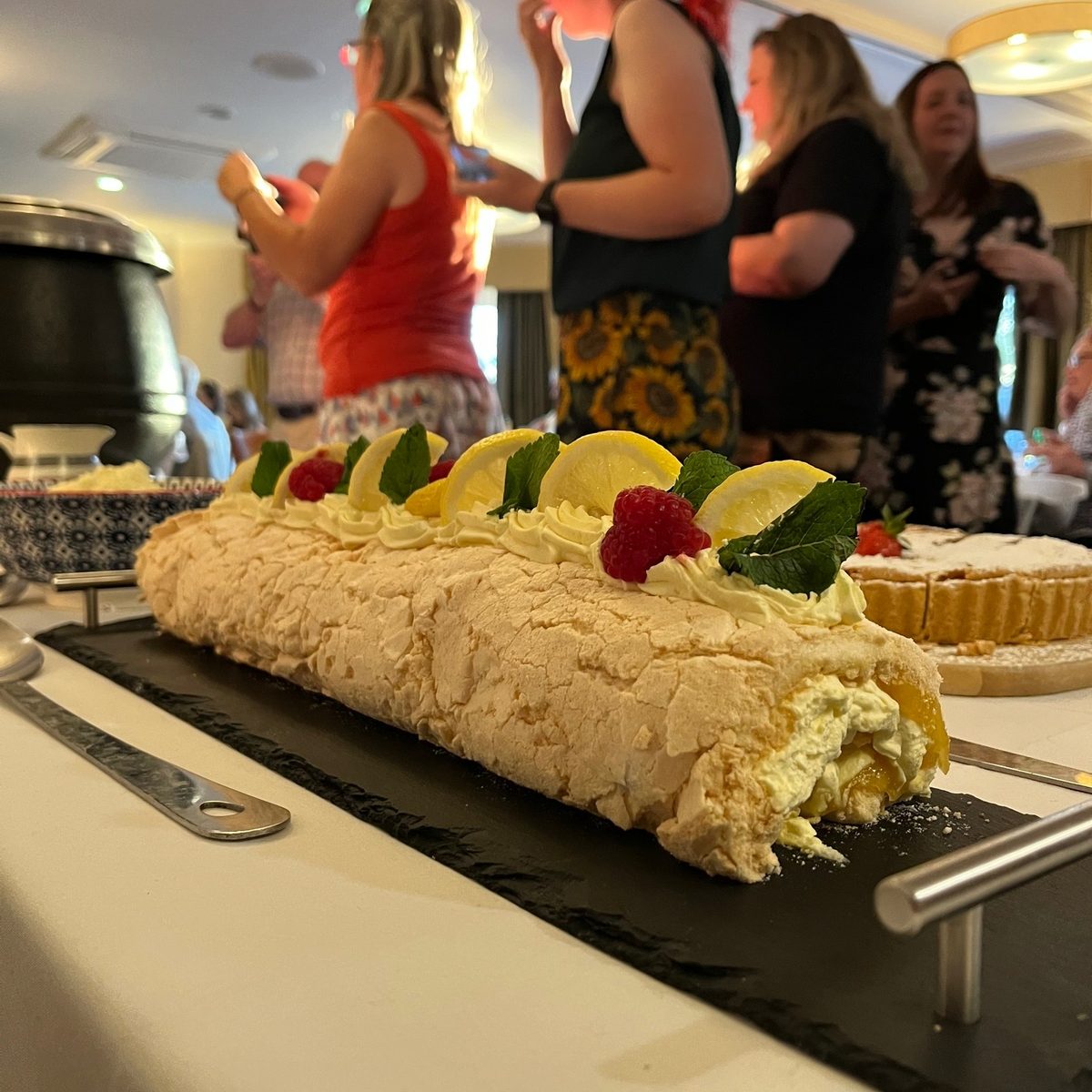 Guests serving themselves from a selection of puddings and desserts at a Pudding Club evening in the Cotswolds
